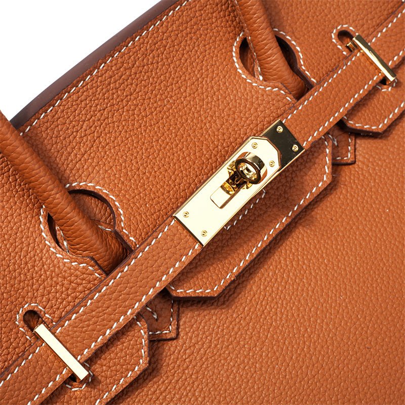 Women’s tan handbag close-up of gold-tone clasp and adjustable strap tabs