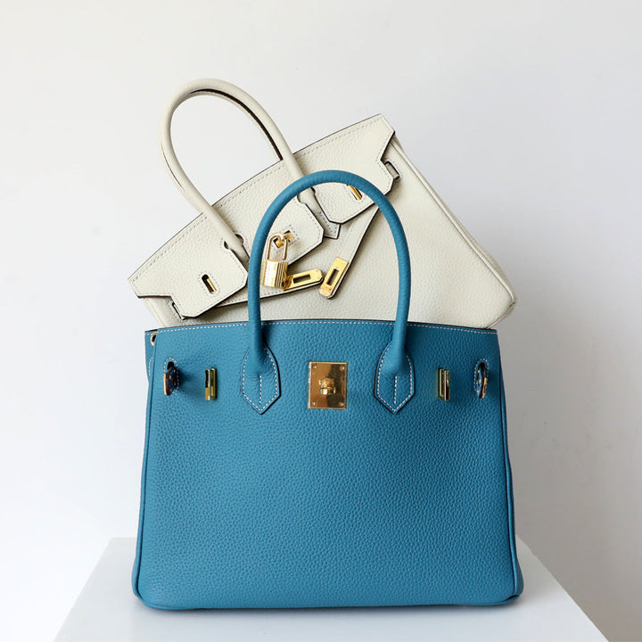 Blue leather satchel handbag with top handles and gold-tone front hardware