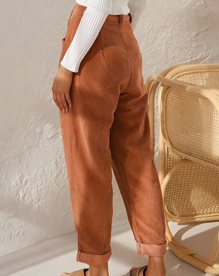 Relaxed corduroy pants in orange with pleated front, button closure, and cuffed ankle hem